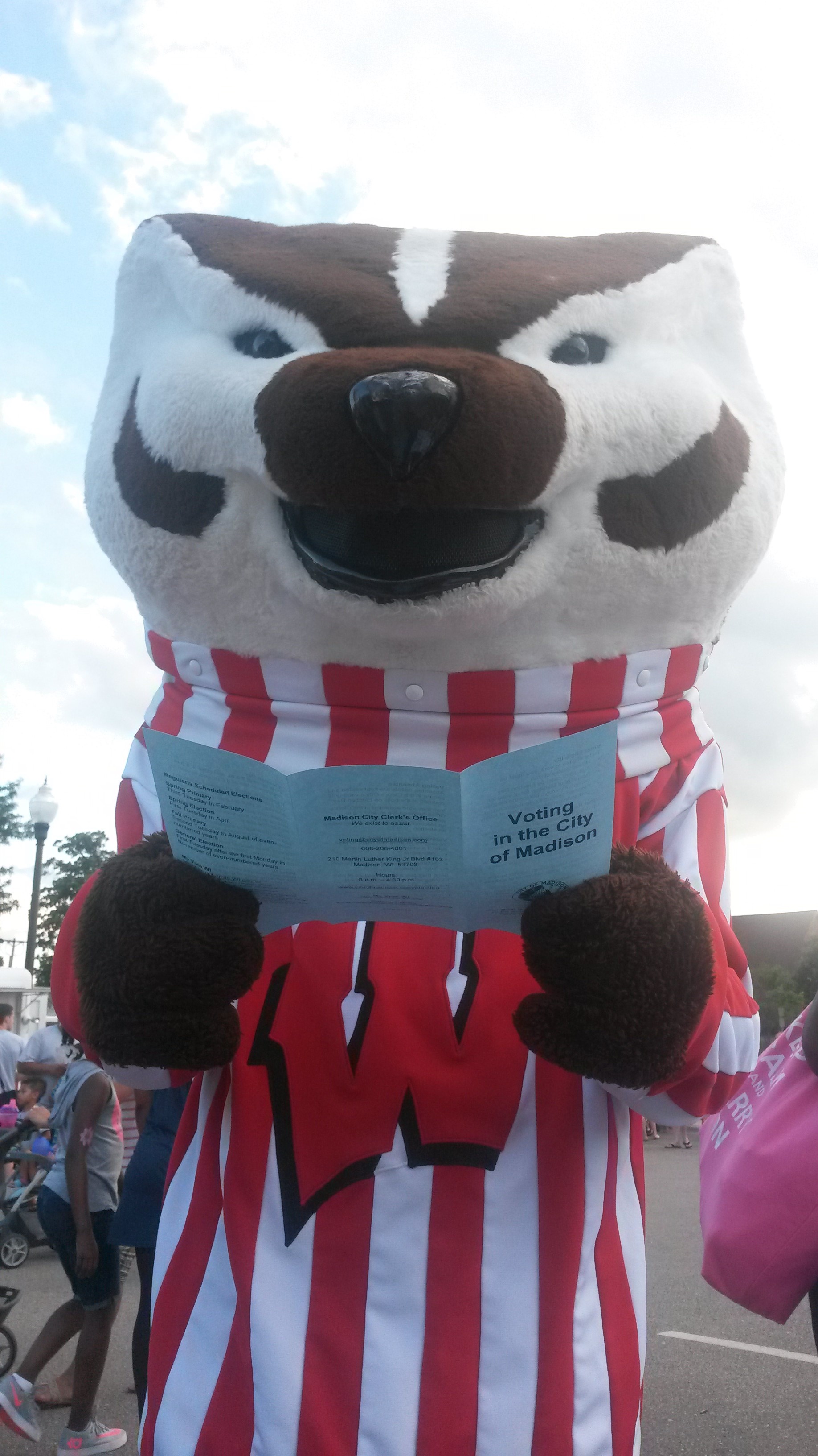 Bucky Badger mascot holding a brochure titled Voting in the City of Madison