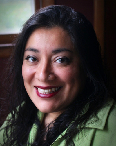 Nancy Saiz smiling, seated in front of a window