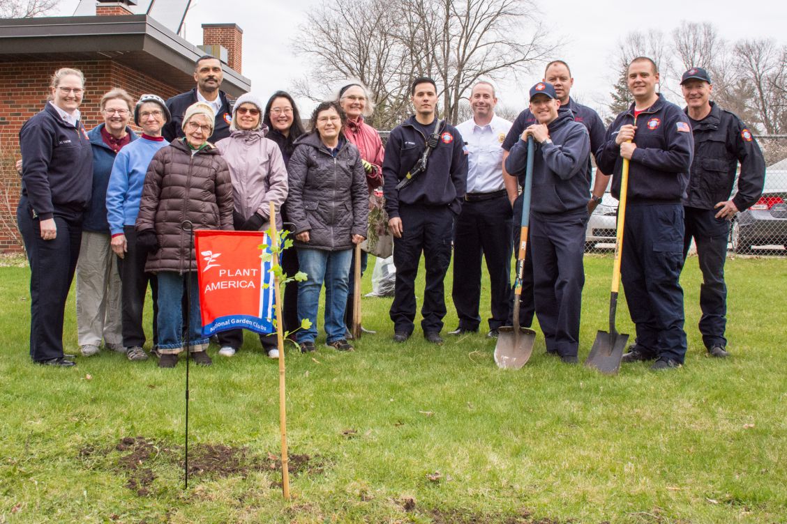 Firefighters and Sunset Garden Club members standing behind new tulip tree