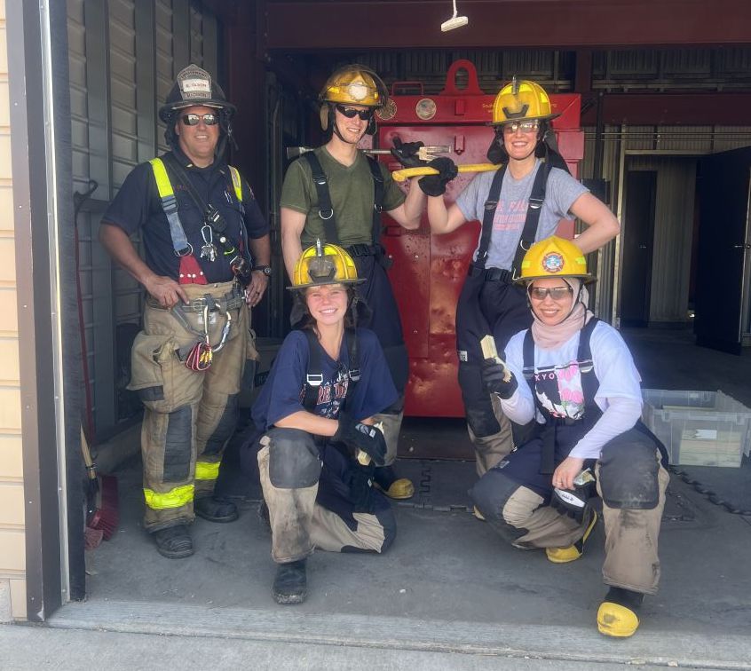 Four medical residents pose in front of large metal door with an MFD training officer