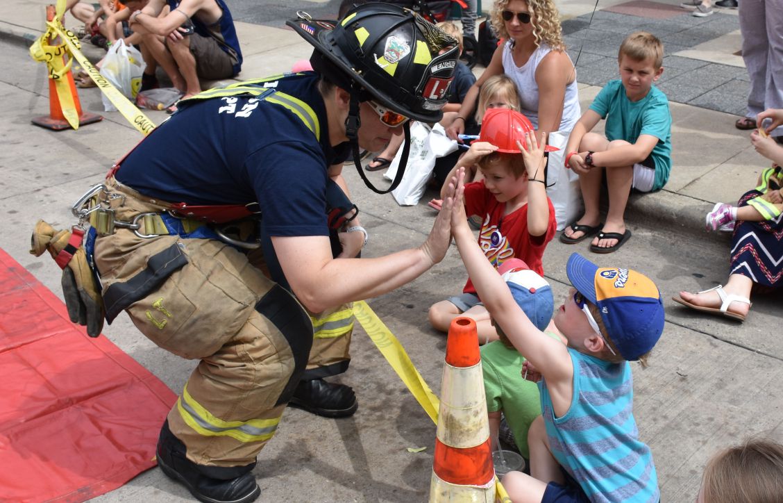 Firefighter high-fiving with a kid at Safety Saturday