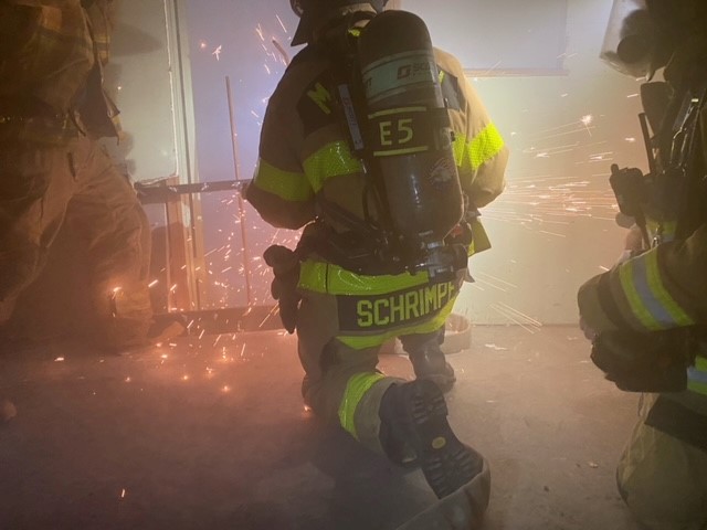 firefighter cutting through metal with sparks flying