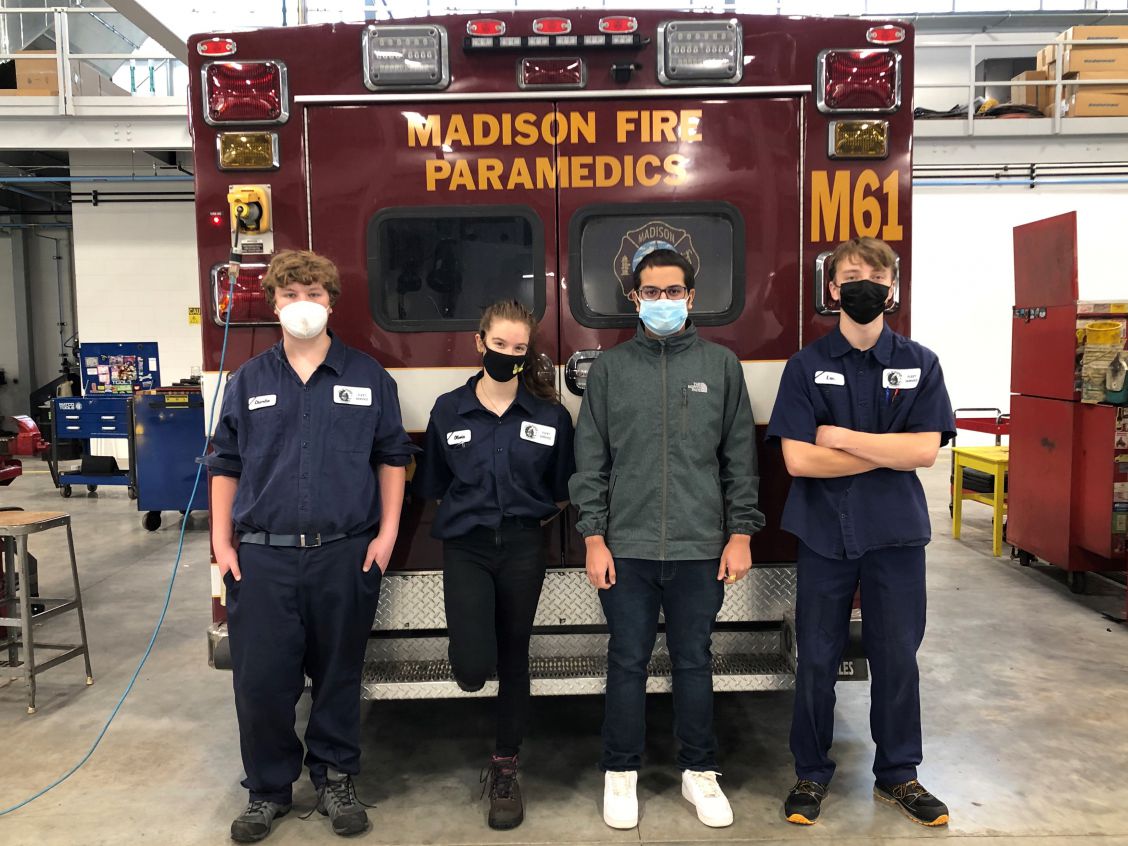 Apprentices Charlie, Olivia, Pranab, and Luc stand in front of a Madison ambulance.