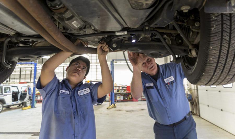 Apprentice and technician work on vehicle