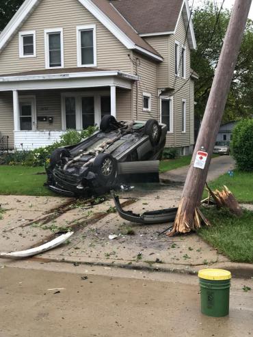 car turned over on front yard with broken power pole