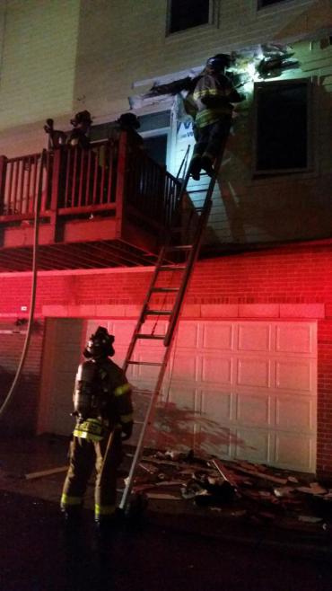 Firefighters on ladder checking building exterior