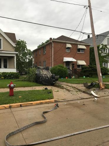 wide shot of overturned car, damaged tree and power pole