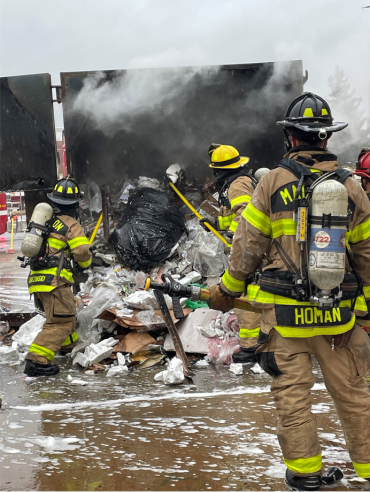 Firefighters overhaul the trash inside the compactor and search for any additional fire