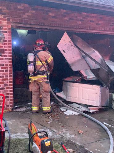 Firefighter standing in garage with damaged garage door