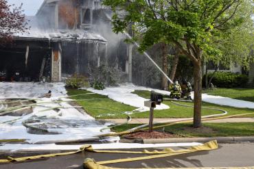 Firefighters spray water and foam on to the house