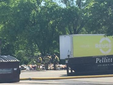 Firefighters stand near the discarded contents of dumpster