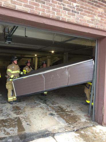 Firefighters removing garage door from apartment building