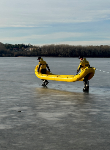 Two Lake Rescue Team members walk the RDC out to the hole in the ice