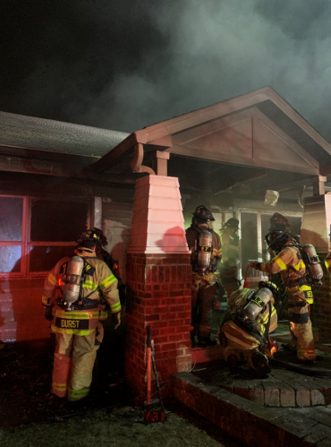 Firefighters on porch with smoke showing