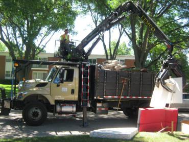 Streets Division employee using the truck-mounted crane to grab large items from the curb
