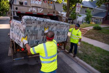 Two hearty Streets Division employees lifting a couch. Remember to follow the guidelines to make their job safer!