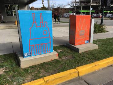 Images of two utility boxes wrapped with Derrick Buish's abstract paintings