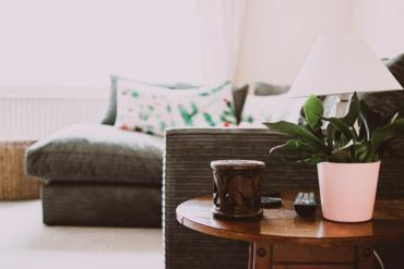 A living room couch and table with a coffee cup and plant