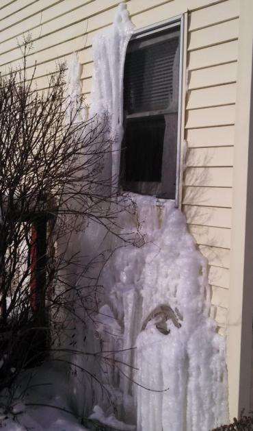 Burst pipe sends ice flow out the window of a vacant home