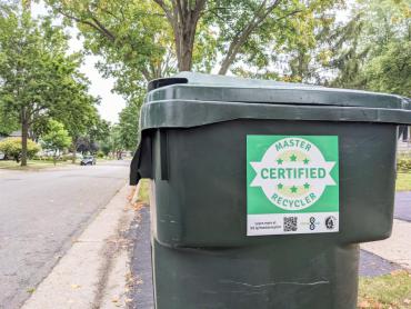 Recycling cart out for pickup with the Certified Master Recycler sticker on its side
