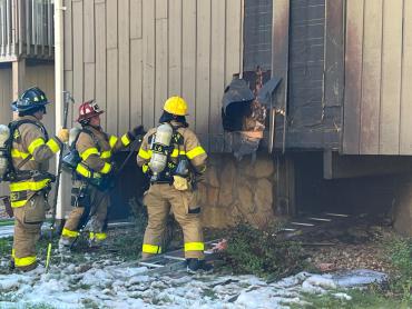 firefighters tear away exterior siding to search for fire spread