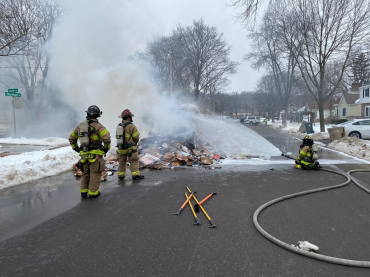 Firefighters spraying foam on pile of recyclables
