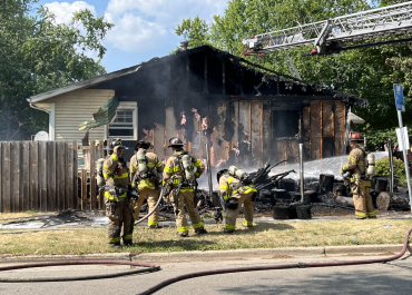 Firefighters spray water on the home siding to prevent rekindling