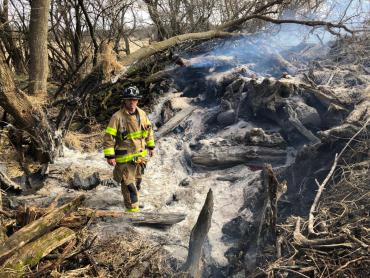 Firefighter standing in burned wood pile