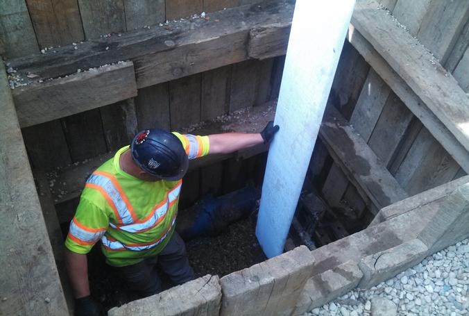 Worker feeds pipe relining material into water main