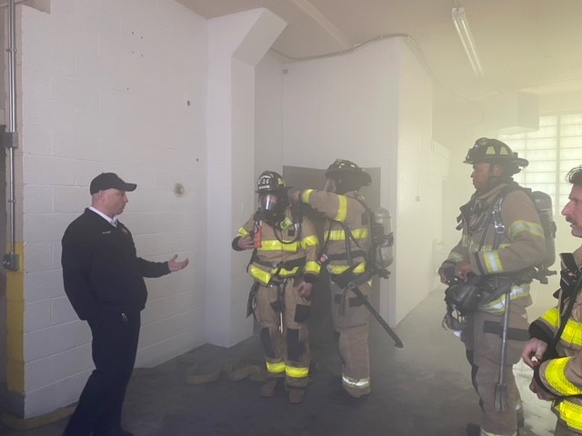 Training officer speaks to firefighting crew before combat drill