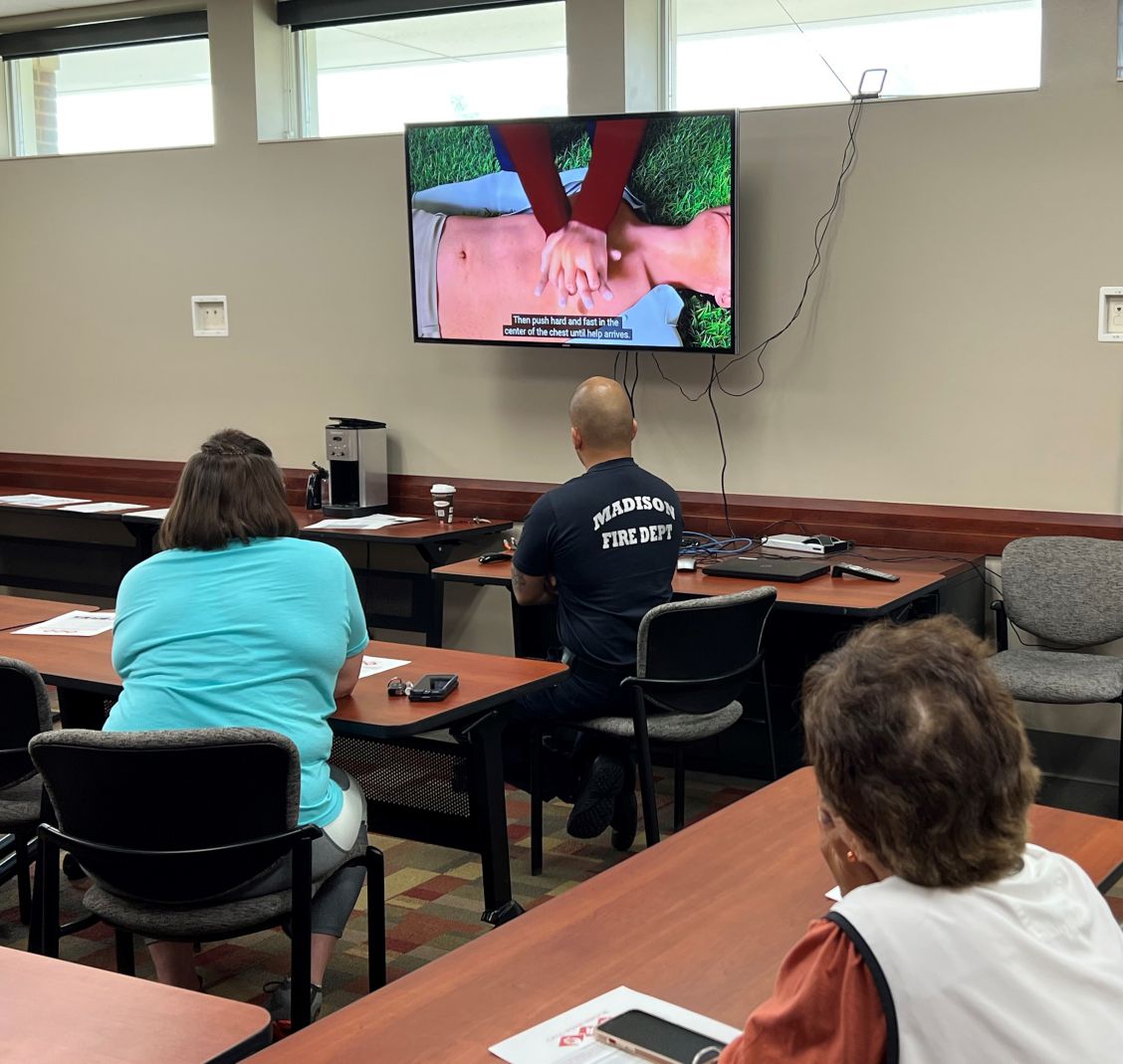 Attendees watch a CPR demo video together