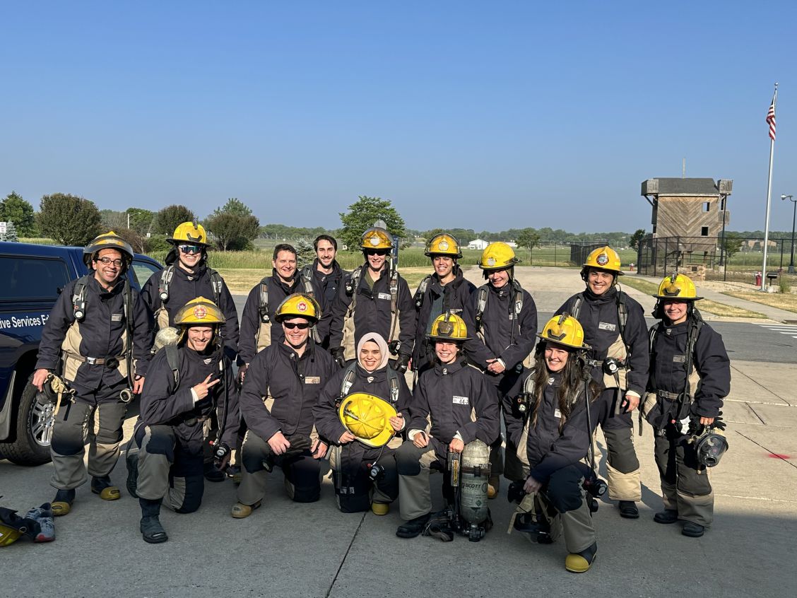 Group of medical students pose in helmets and fire gear for "Doc Ops Day"