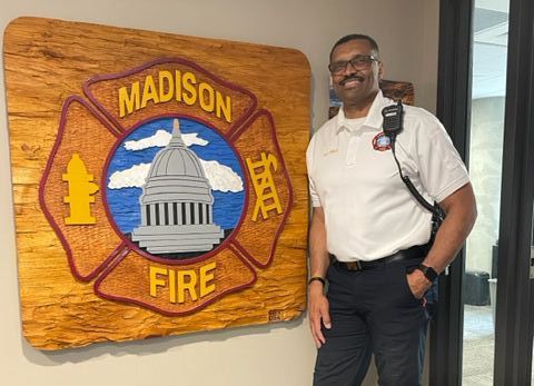 Art Price stands next to large Madison Fire Department emblem