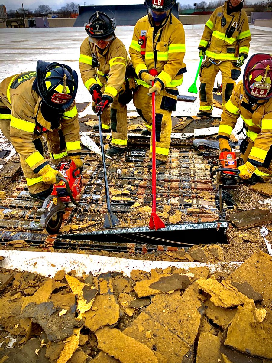 multiple firefighters peel away corrugated metal