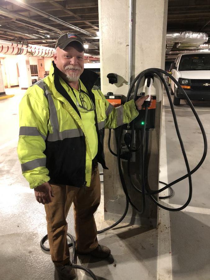 Matt Parks standing next to an electric vehicle charging station