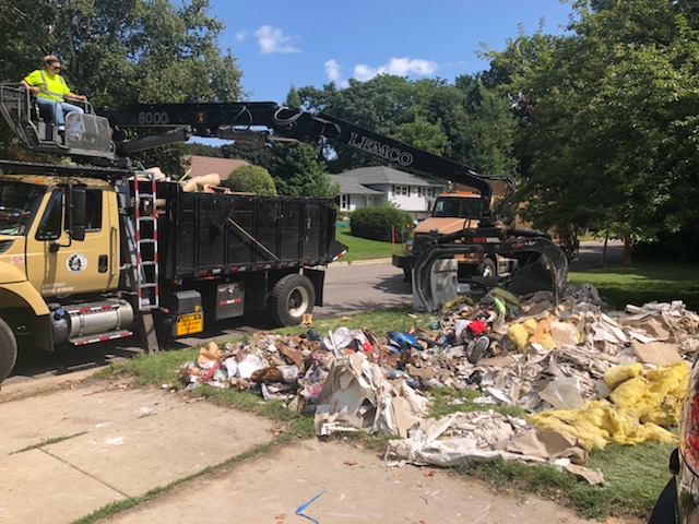 A Streets Division truck picks up large items from a front yard after the August 2019 flood.