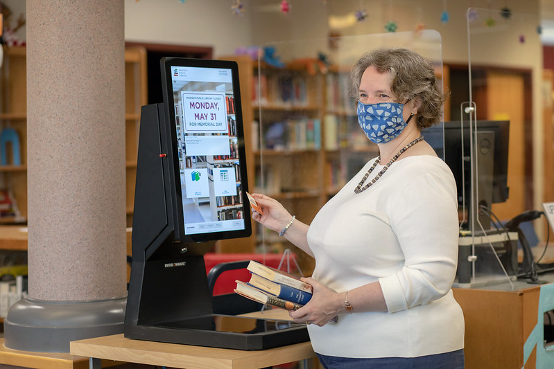 Mayor Rhodes-Conway using the new self check stations right before libraries reopened for full service in May 2021 during COVID