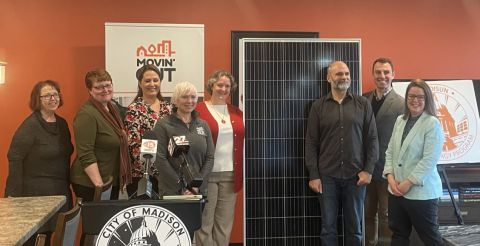 Mayor Rhodes-Conway stands near solar panel with Movin' Out staff