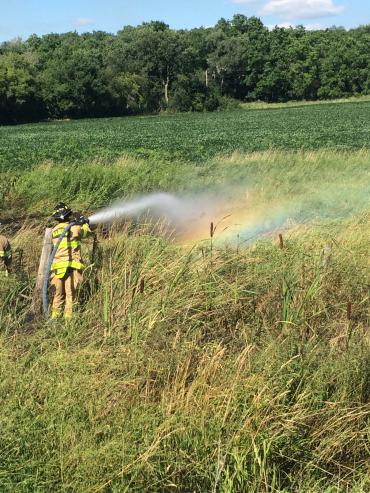 Firefighter enters grassy area to douse the fire