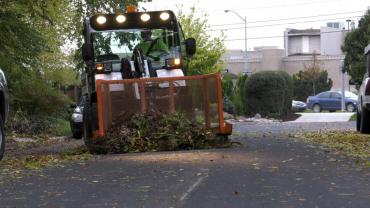 A pile of leaves and yard waste being pushed by a Streets Division collection vehicle. 