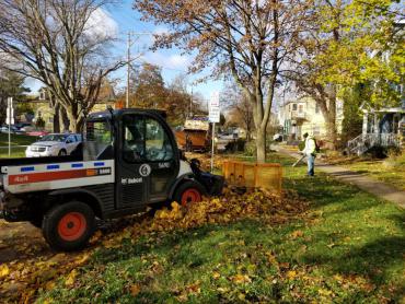 Here is one of the "pushers" dragging a pile of leaves from a terrace. In the distance there is the collection truck that will receive the leaves.  This is a lucky crew because it has a third person for the backpack leaf blower to help tidy up the terrace.