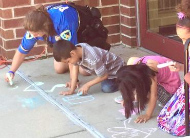 Detective Amanda Analla sidewalk chalks with children in the Madison community.