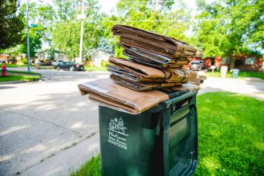 Cardboard correctly piled up on top of a recycling cart.