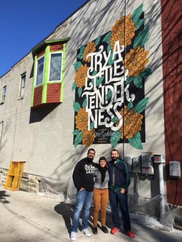 Artists Jackson Alves, Cyla Costa, with project organizer Henrique Nardi stand before Otis Redding memorial mural