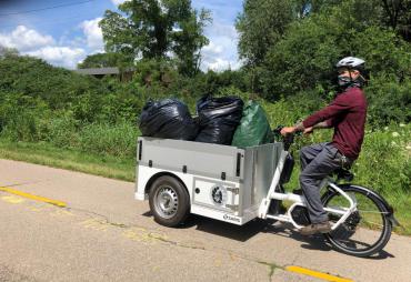 City employee using E-Bike to remove Japanese Hedge Parsley along bike path