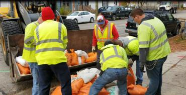 Photo of sandbag collection crew from 2018 lifting sandbags into a loader