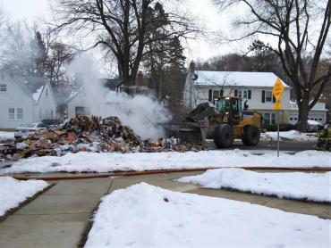 Loader from Streets Division assisting in moving recyclables so firefighters can put out the flames