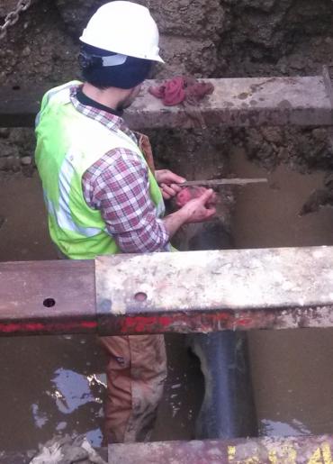 Water Utility employee Chris Villaneueva wade into sinkhole to reach broken water pipe