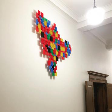 Image of About the Future (Dreaming) by Victor Castro (TetraPAKMAN), a bright sculptural assemblage created out of industrial zip ties and the plastic shipping material that lab tubes  come in. The pieces are installed high up on the hallway walls of the 2nd floor of the Madison Municipal Building