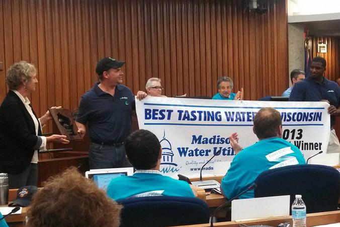 Two Madison Water Utility employees hold banner recognizing Madison's Best Tasting Water win